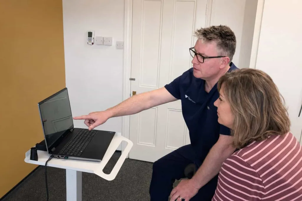 A dentist showing treatment options on a laptop