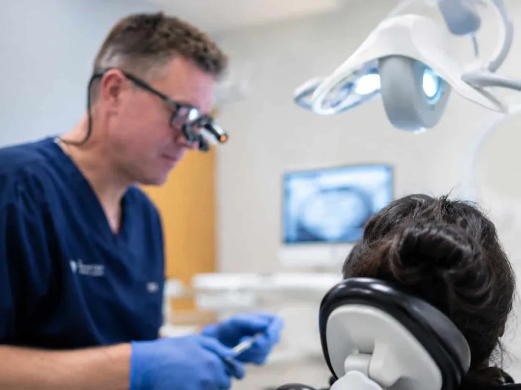 A dentist in loupes treating a patient