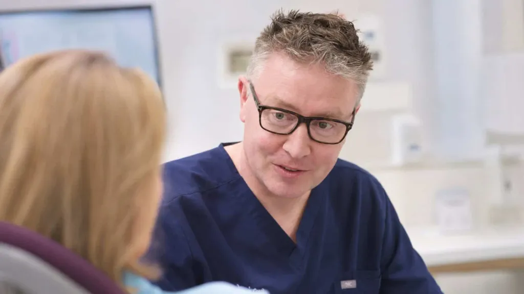 A dentist and patient reviewing images on screen
