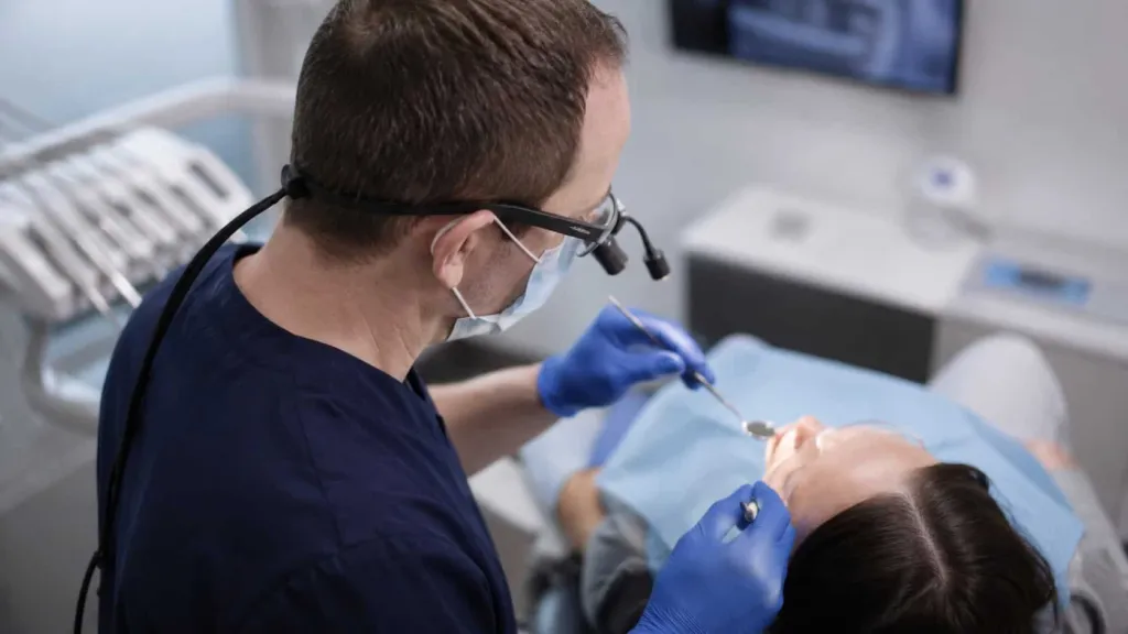 A dentist in loupes treating a patient