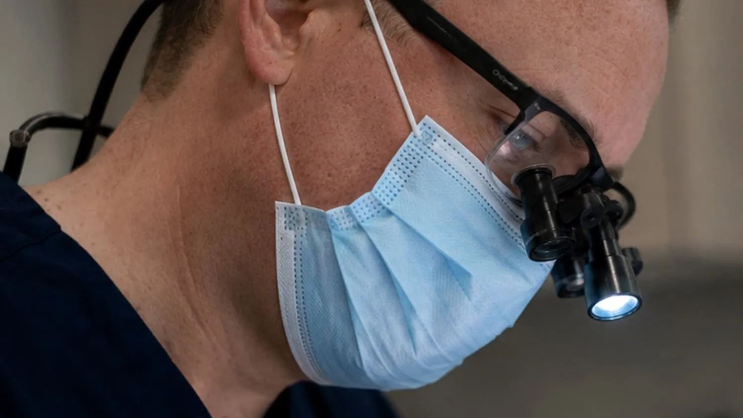A dentist in a mask and surgical loupes
