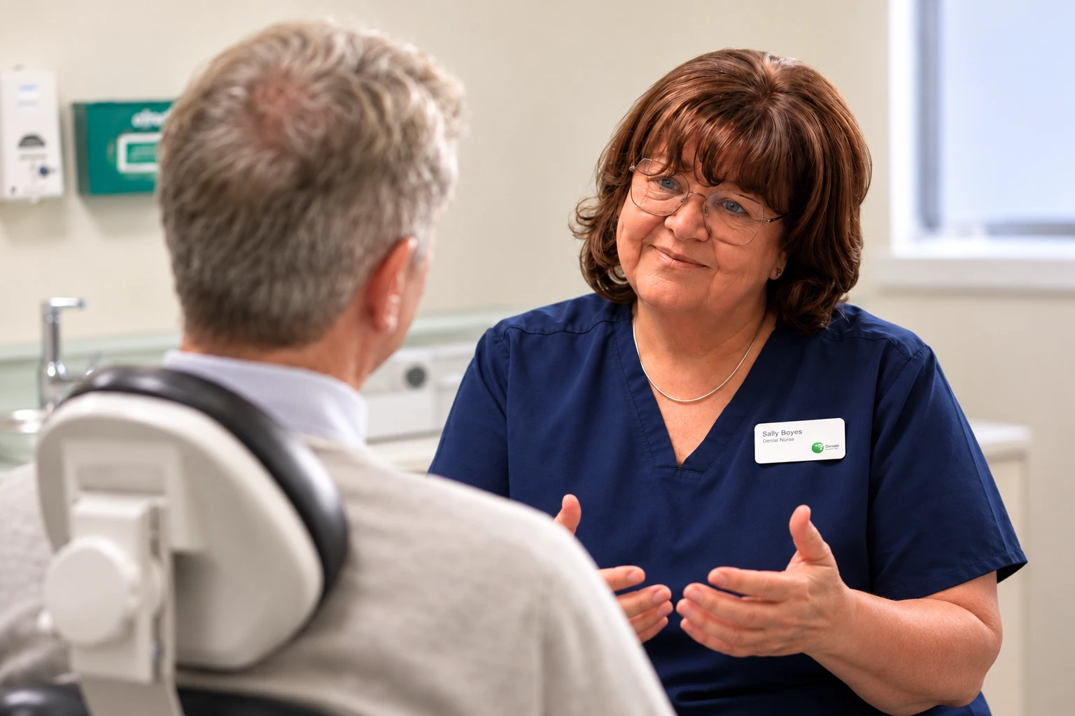 Sally Boyes talking with a patient in the treatment room